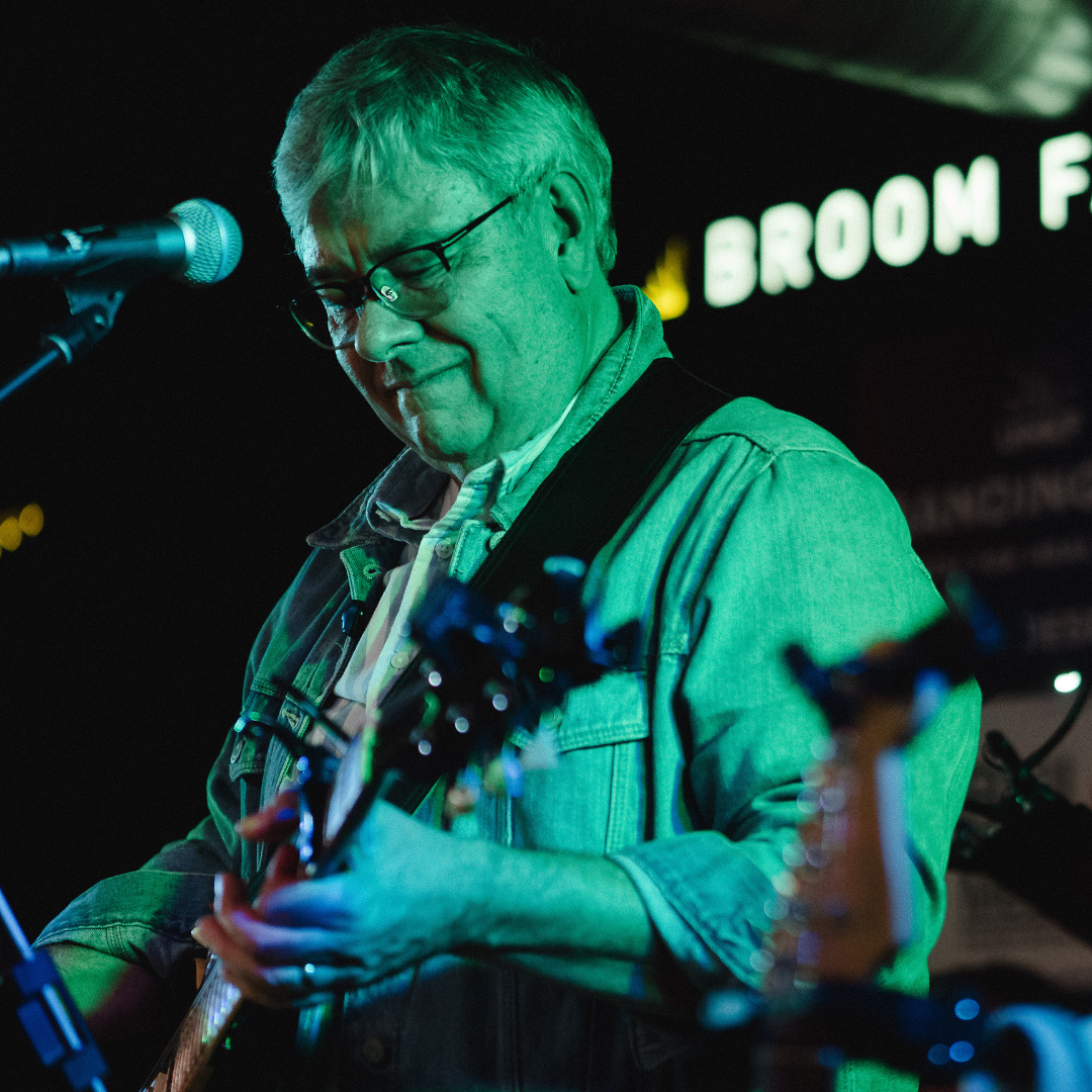 Dr. Evans playing guitar under a green light.