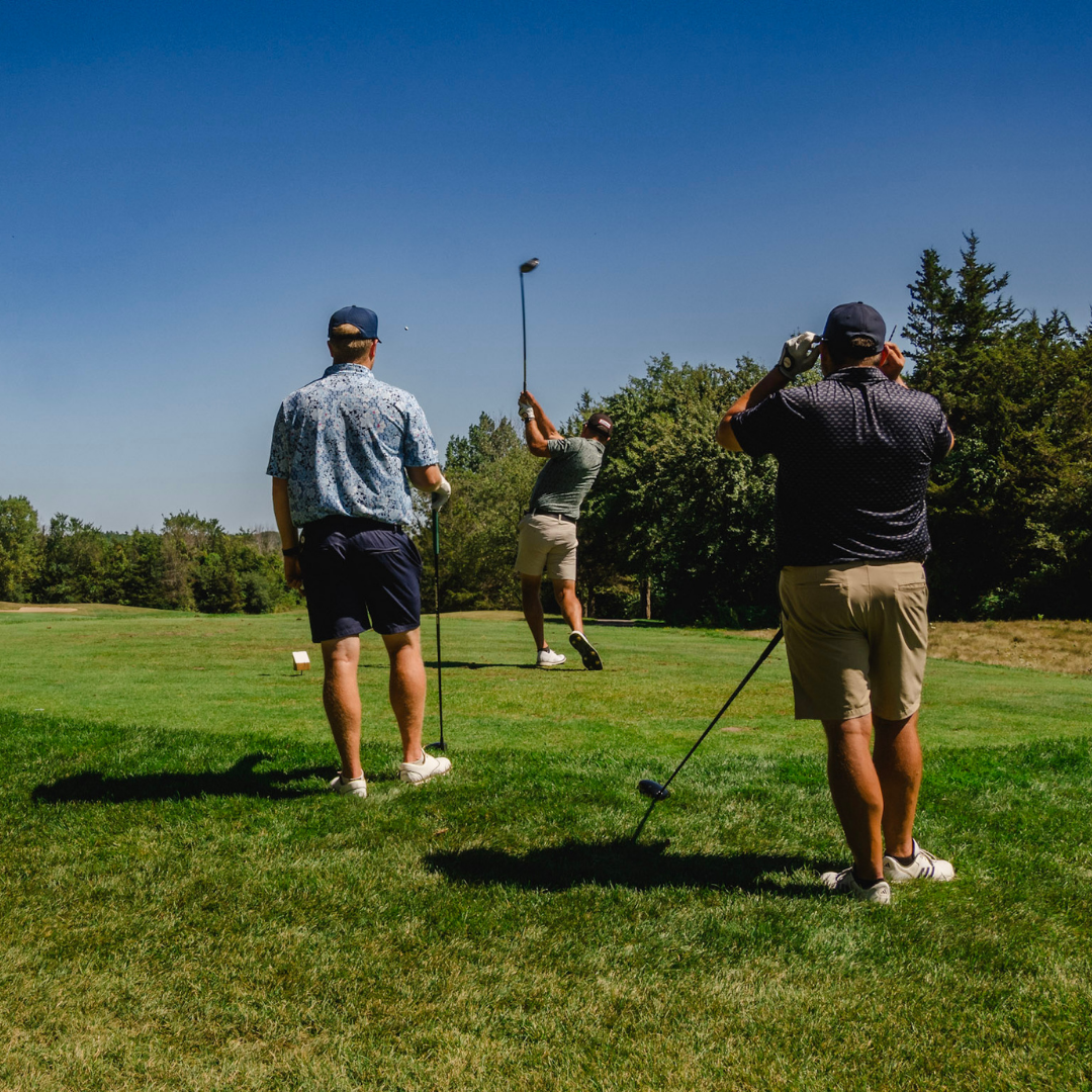 Golfers watching another player swing