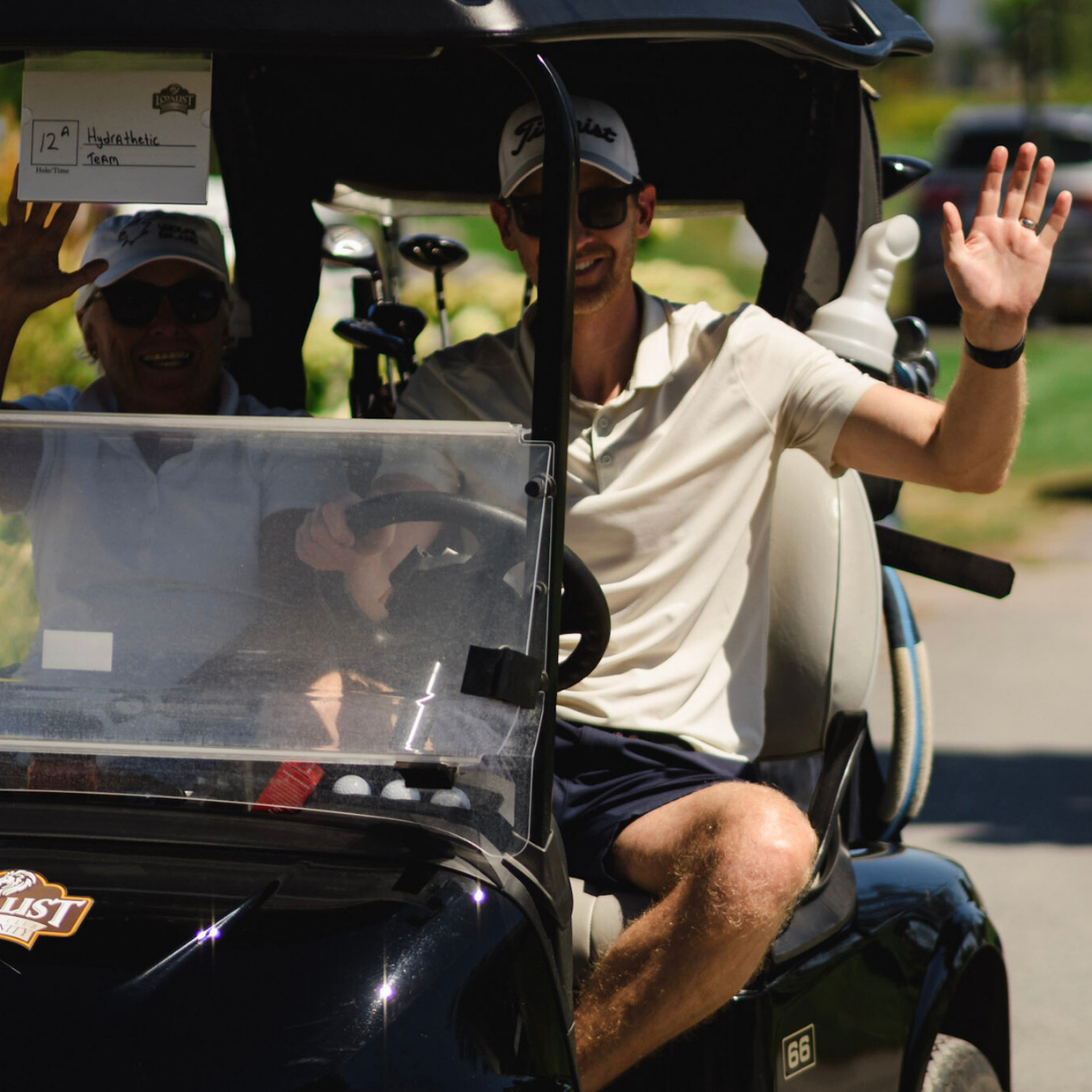 Golfers waving from cart.