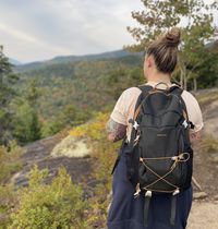 Megan wearing a backpack while looking out at the mountains.