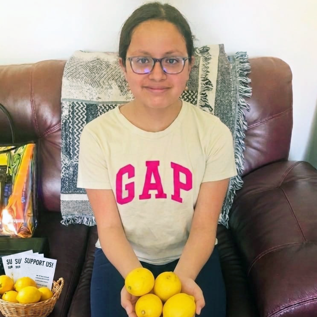 Image of thirteen year old Olivia smiling and holding lemons.