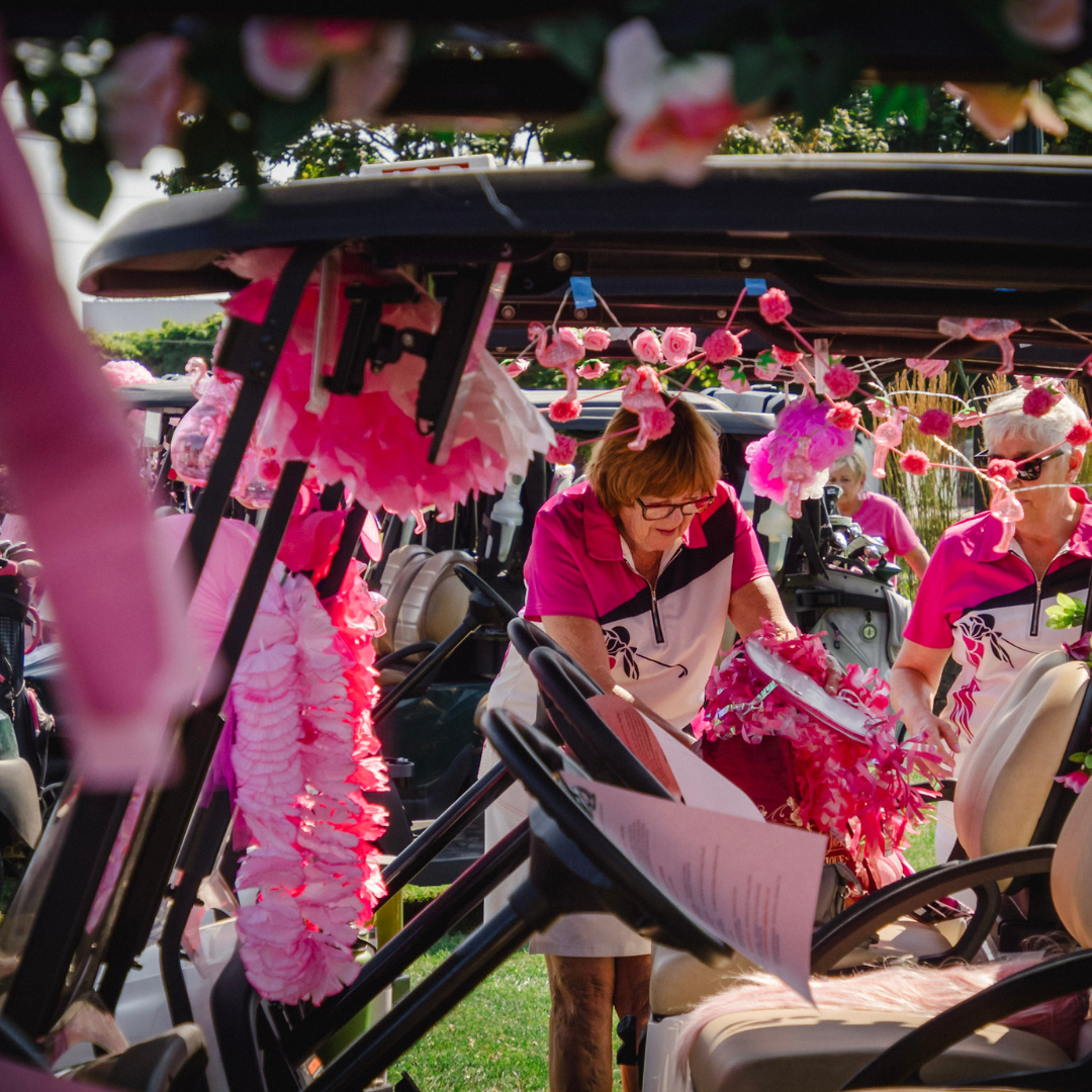 Woman decorating golf cart with pink decorations