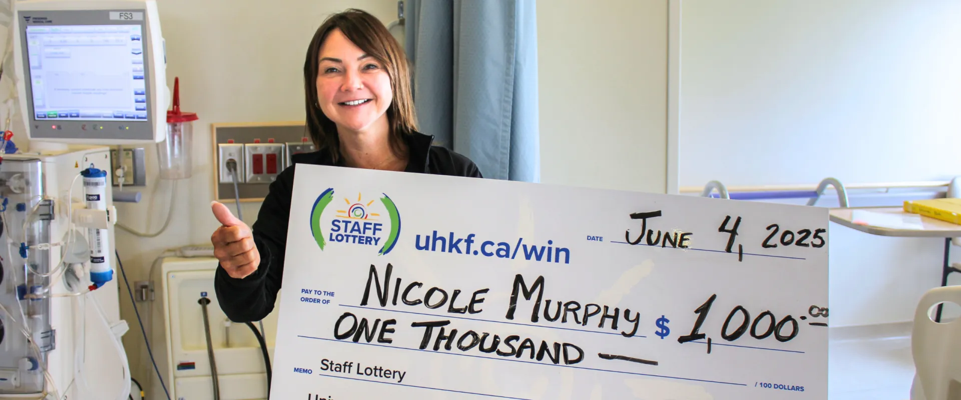 Nicole Murphy holding her $1000 staff lottery cheque.