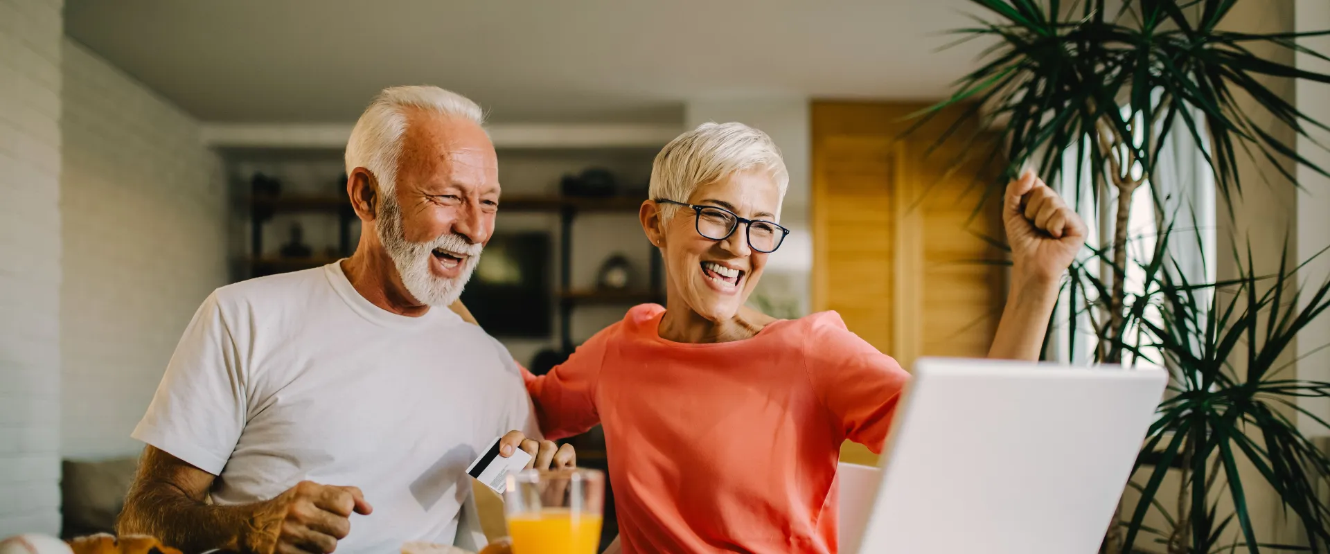 Older couple sitting at their table and working on a laptop.