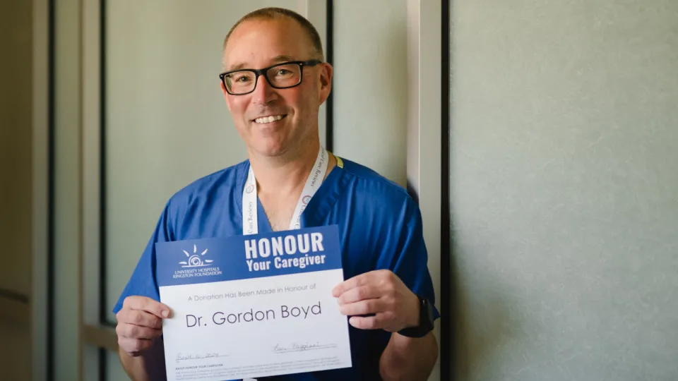 Dr. Gordon Boyd smiling and holding an Honour Your Caregiver certificate.