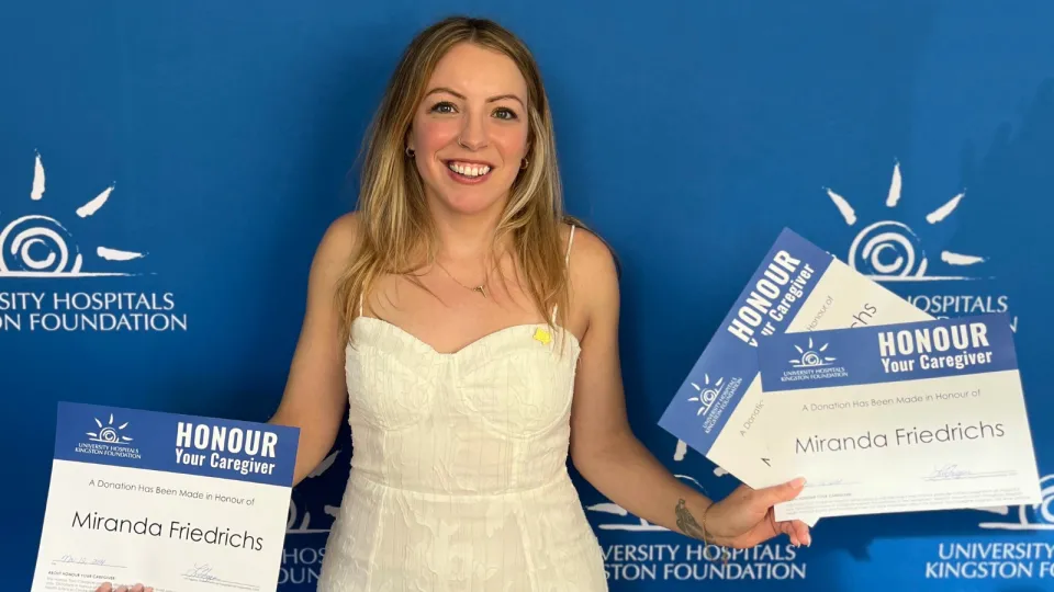 Miranda Friedrichs holding HYC certificates in front of a blue wall.