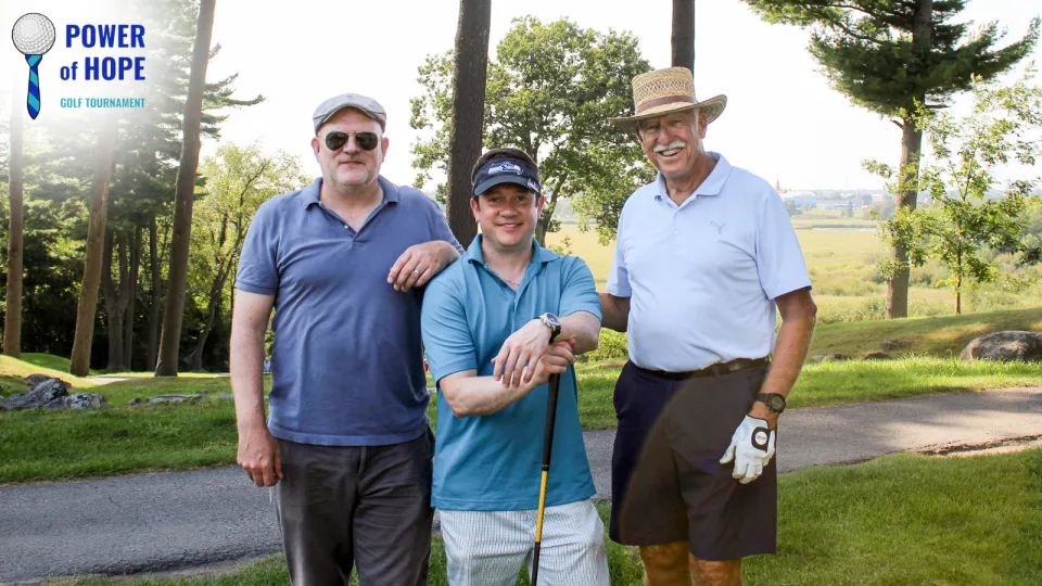 Three men in blue golfing shirts with clubs.
