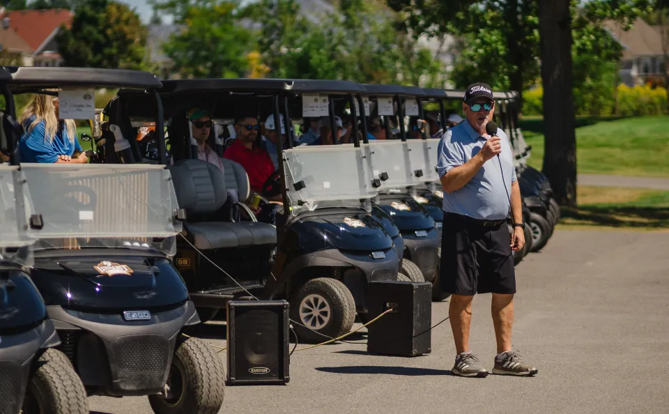 Man holding microphone talking to golfers