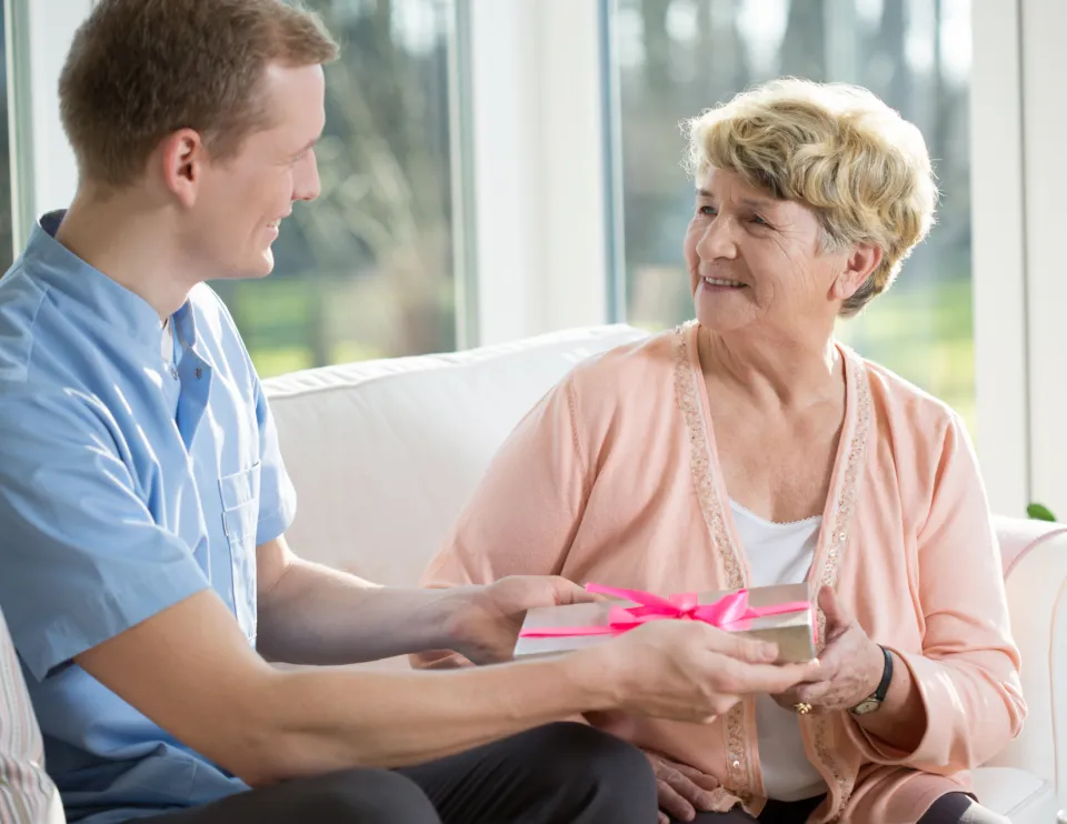 A person hands a gift to a woman.