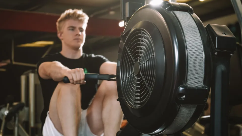 Man using rowing machine in gym.