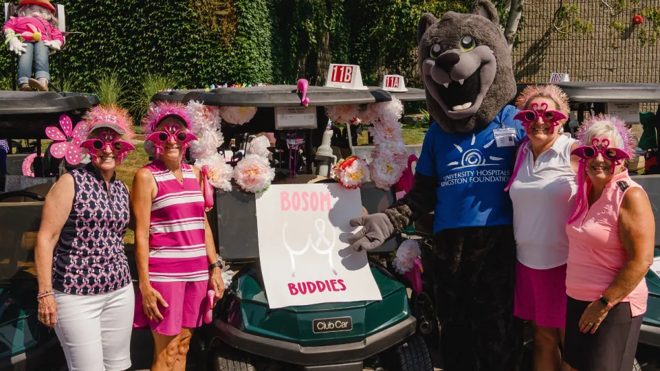 UHKF Mascot Asher with golfers at the Rose of Hope Golf Tournament in pink golfing gear.