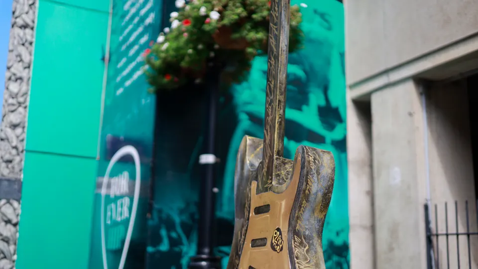 Outside Hotel Dieu Hospital is a guitar art installation. The guitar stands at six feet tall and incorporates EGK lines in the design, weaving in the themes of healthcare to the Kingston story of music and art. In the background you see a wall wrap promoting The Tragically Hip's ten year anniversary since their last show.