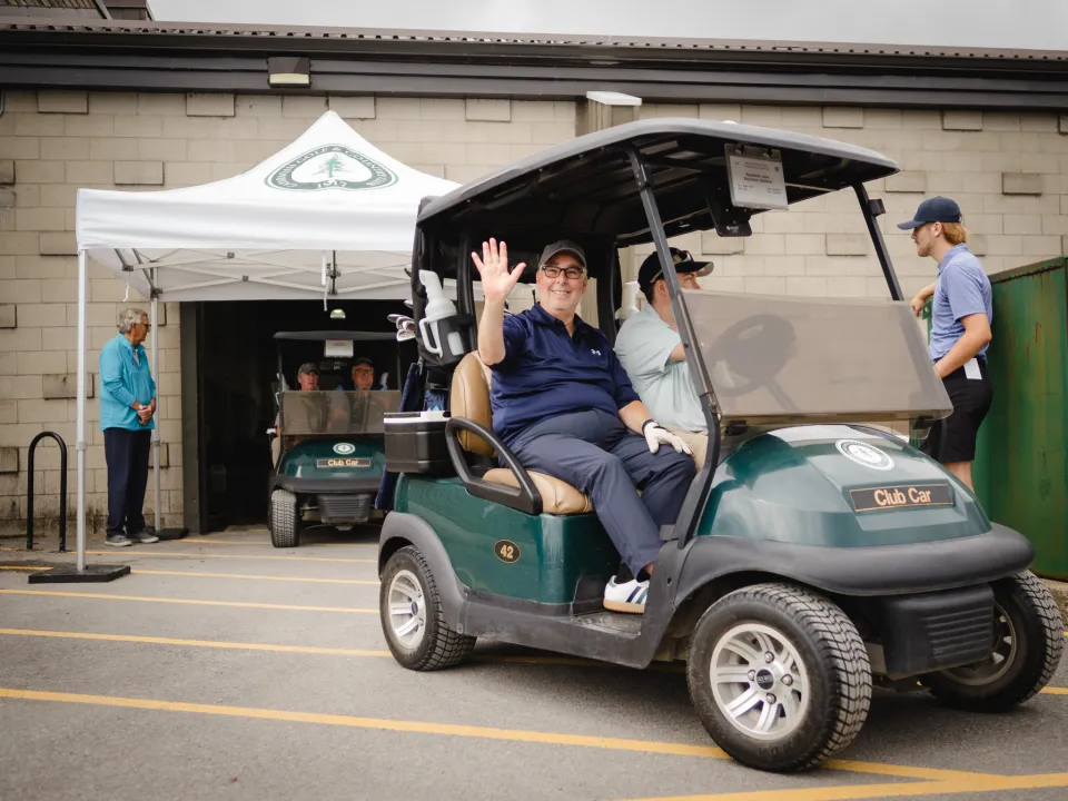 Golfer John Raymond waves as he heads out to the course.