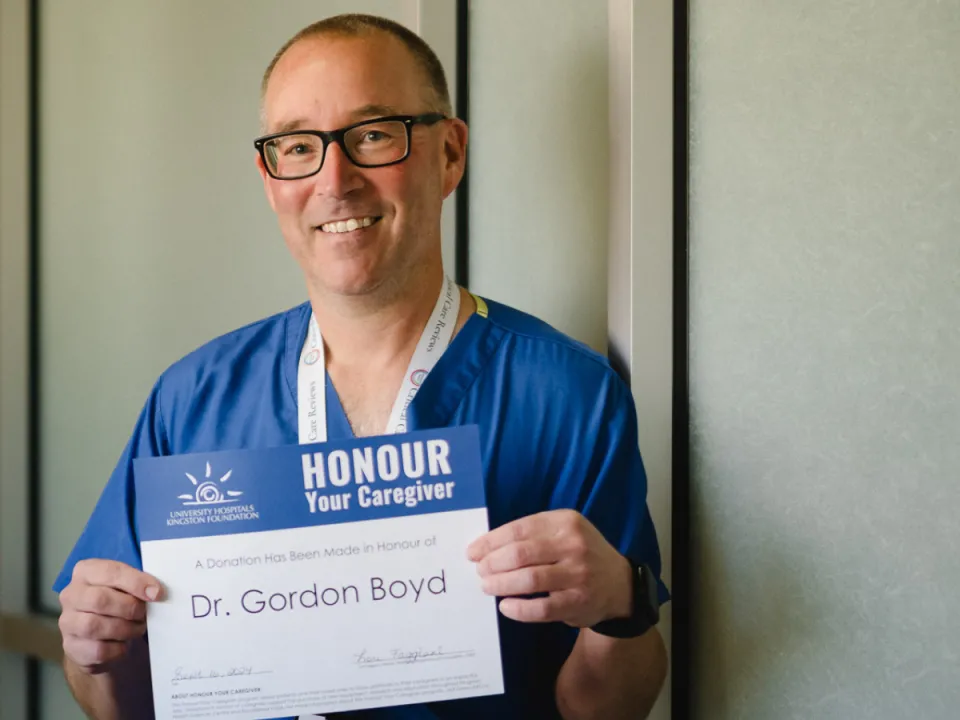 Dr. Gordon Boyd smiling and holding an Honour Your Caregiver certificate.