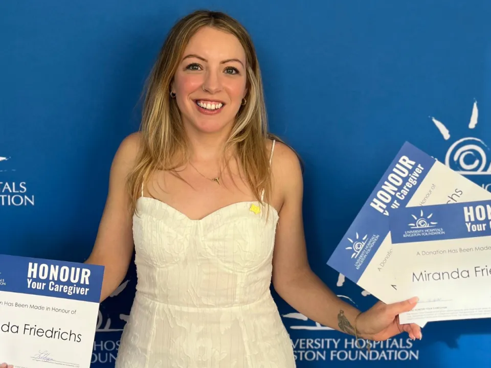 Miranda Friedrichs holding HYC certificates in front of a blue wall.