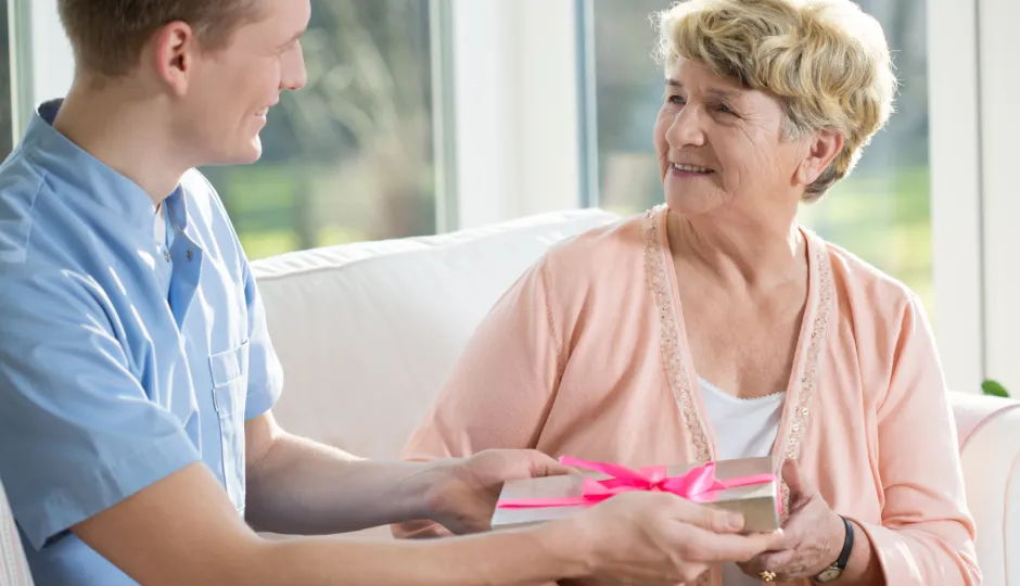 A person hands a gift to a woman.