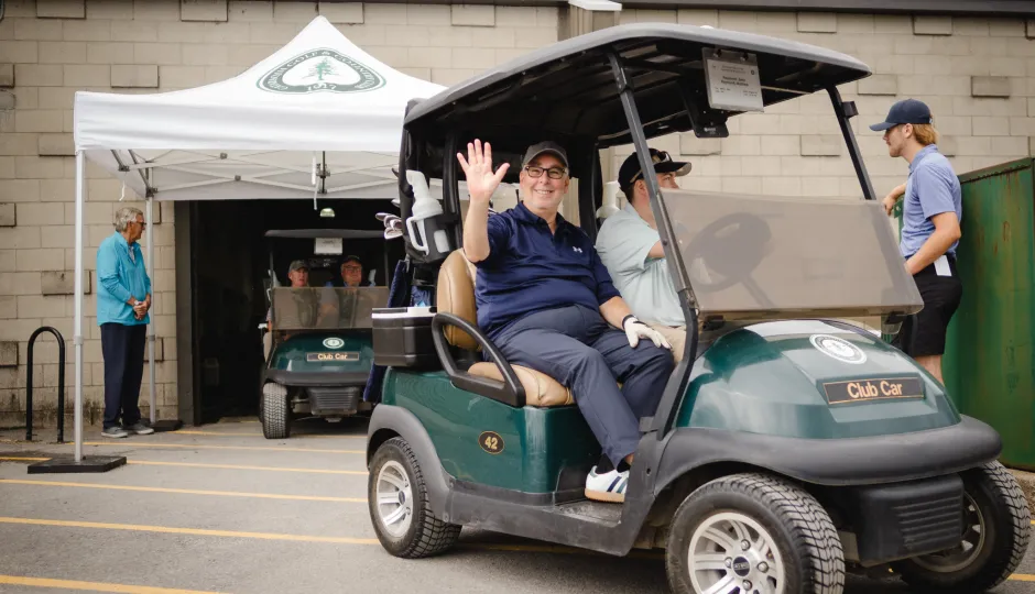Golfer John Raymond waves as he heads out to the course.