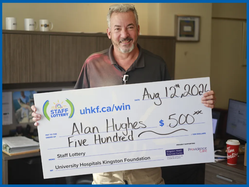 Alan Hughes posing with a big cheque.