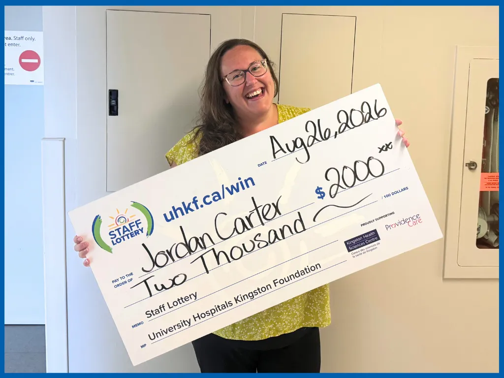 Jordan Carter holding big staff lottery cheque for $2000.