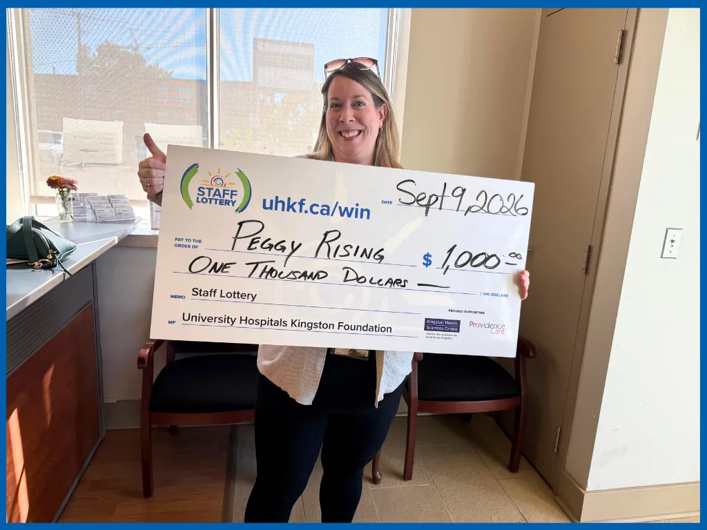 Peggy Rising holding a big Staff Lottery cheque