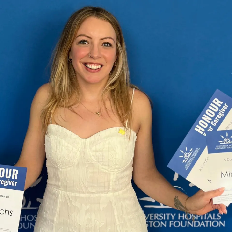 Miranda Friedrichs holding HYC certificates in front of a blue wall.