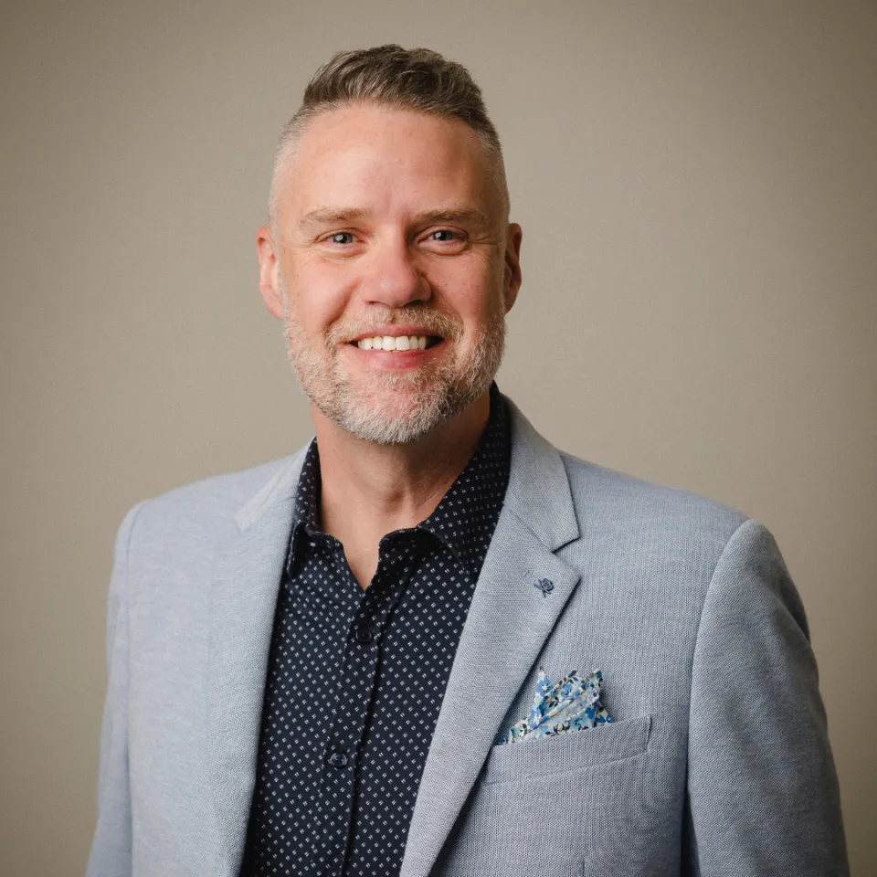 Jeff Doner wearing a grey suit and smiling at the camera.