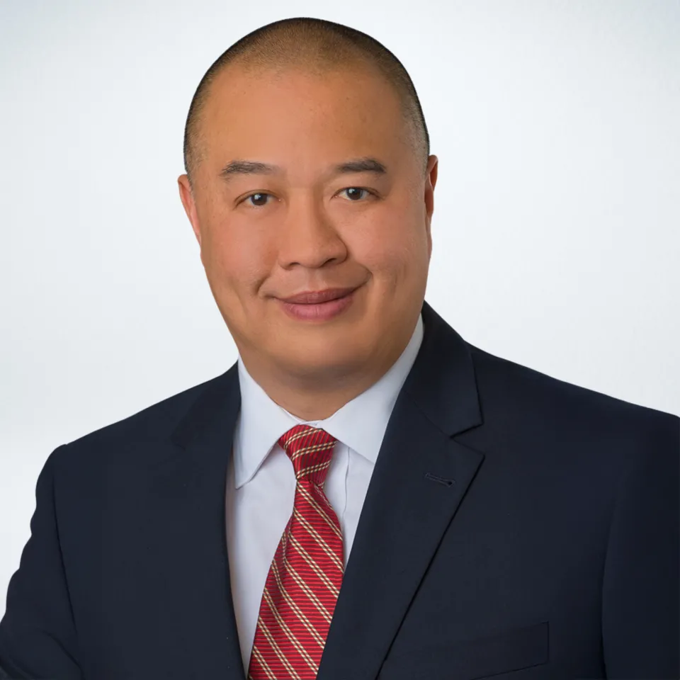 Headshot of Gordon Lee wearing a navy suit with a light blue dress shirt and red tie.