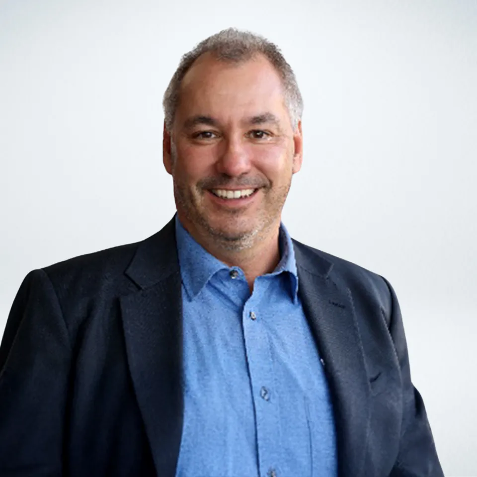 Headshot of Steven Millan wearing a navy blazer and blue dress shirt.