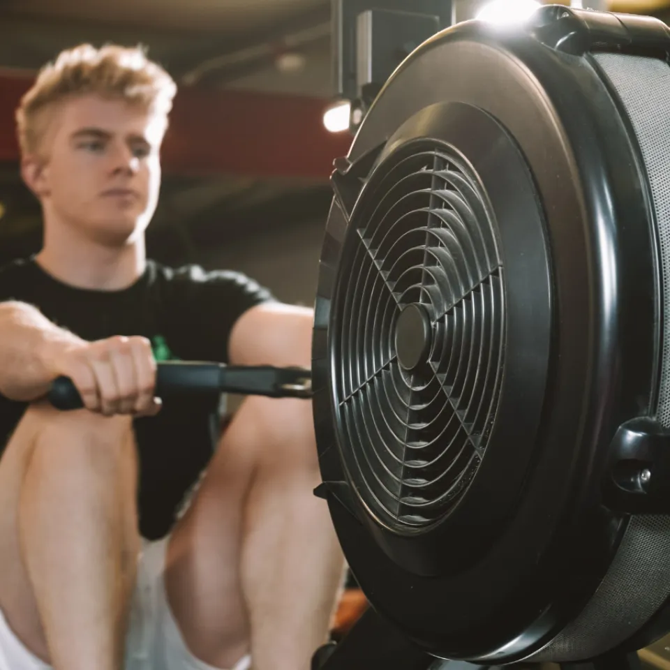 Man using rowing machine in gym.